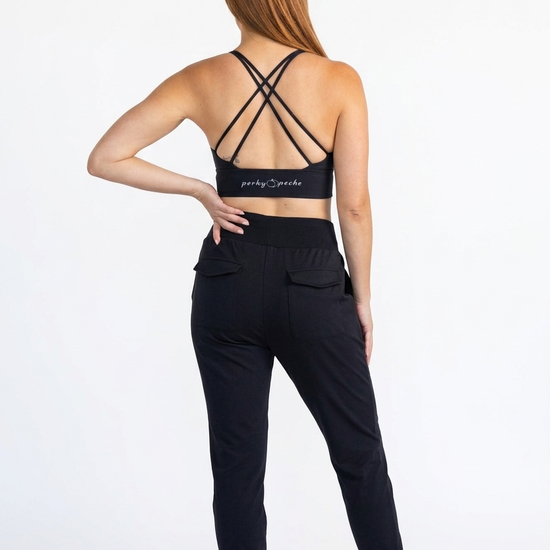 Woman wearing a black sports bra and jogger pants with a visible brand logo on a white background