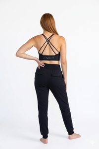 Woman wearing a black sports bra and jogger pants with a visible brand logo on a white background