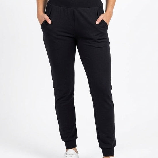 Person wearing black jogger pants and a black crop top on a white background