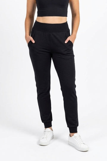 Person wearing black jogger pants and a black crop top on a white background