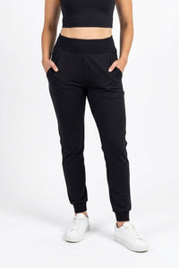 Person wearing black jogger pants and a black crop top on a white background