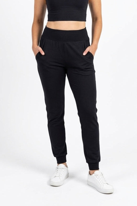 Person wearing black jogger pants and a black crop top on a white background