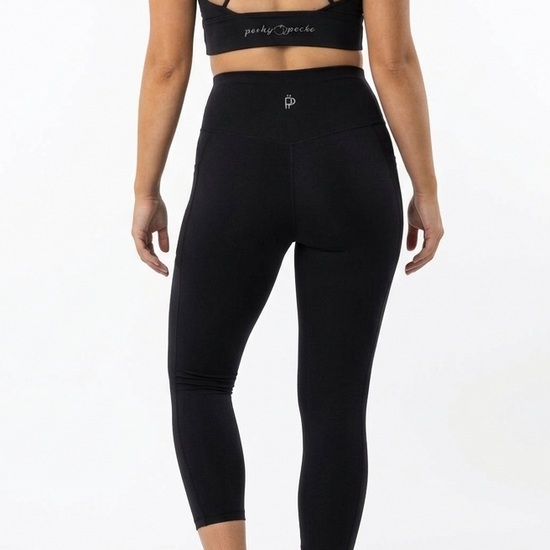 Person wearing a black sports bra and leggings set on a white background