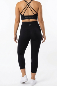 Person wearing a black sports bra and leggings set on a white background