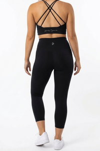 Person wearing a black sports bra and leggings set on a white background