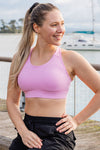 Woman wearing a pink high coverage sports bra.