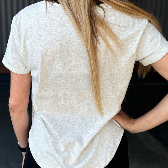 Woman wearing a grey t-shirt with scoop neck.