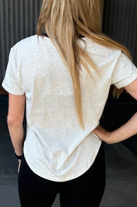 Woman wearing a grey t-shirt with scoop neck.