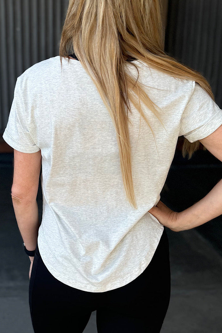 Woman wearing a grey t-shirt with scoop neck.