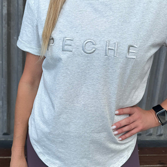 Woman wearing a grey t-shirt with scoop neck.