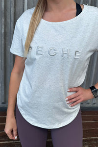 Woman wearing a grey t-shirt with scoop neck.