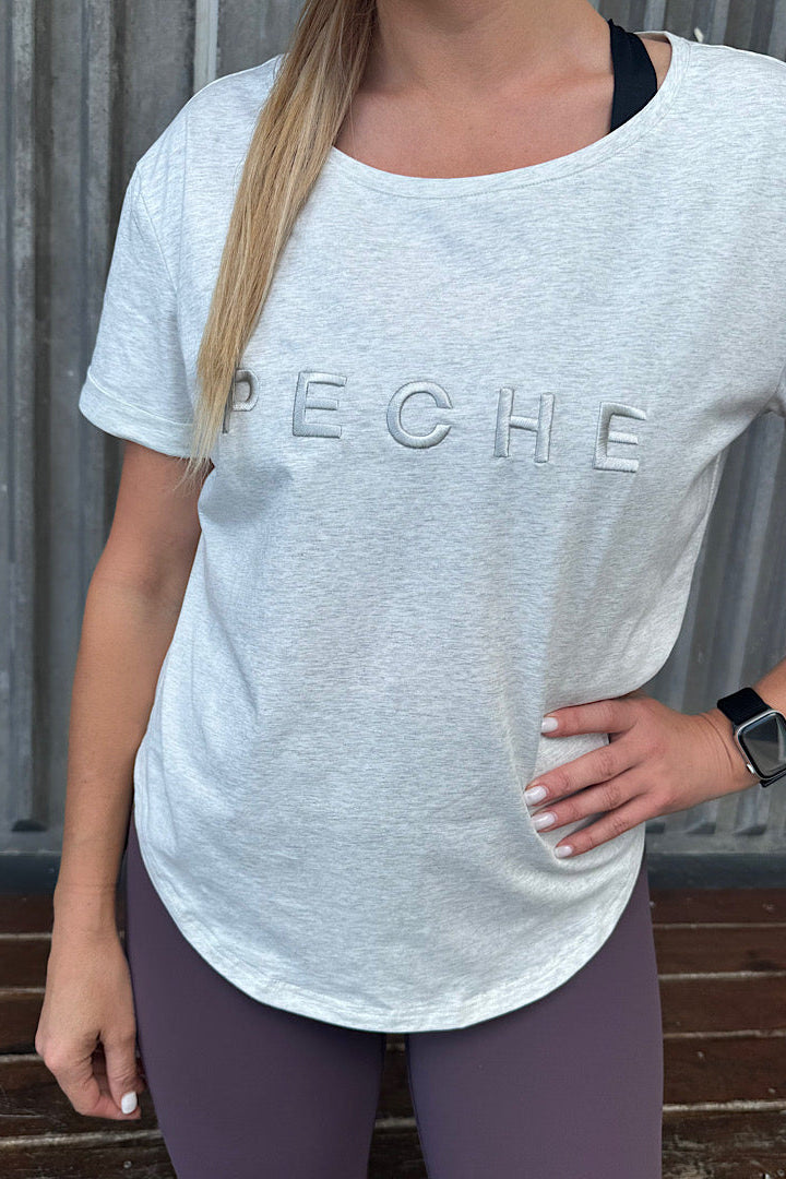 Woman wearing a grey t-shirt with scoop neck.